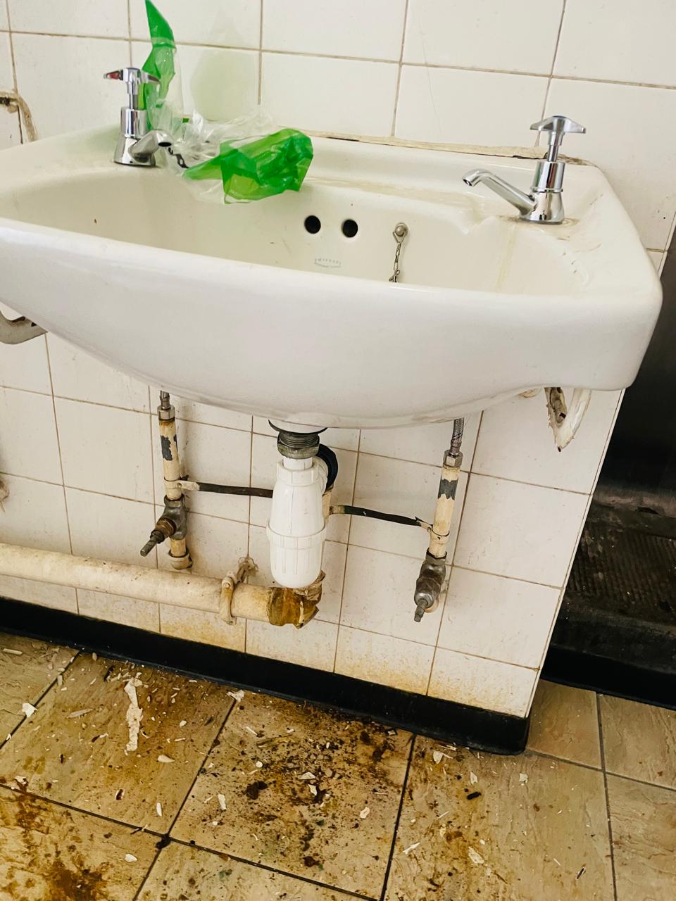 Basin with visible plumbing connections in a tiled washroom